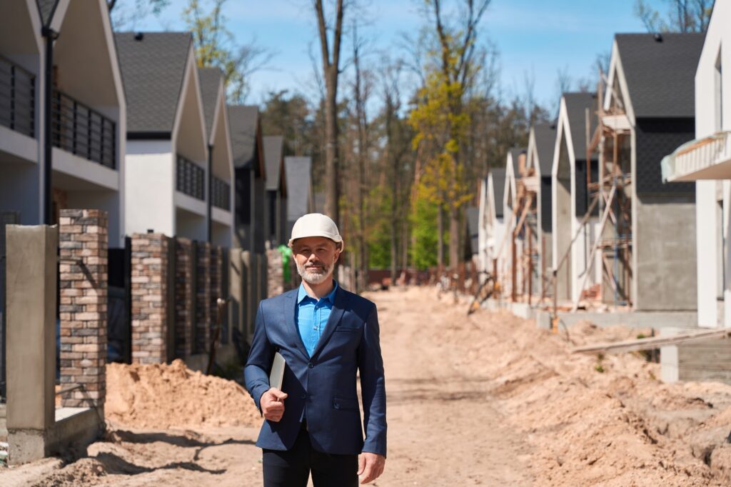 Business man housing developer in hardhat standing at construction site